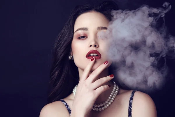 Beautiful sensual woman with dark hair and bright makeup with bijou in smoke — Stock Photo, Image