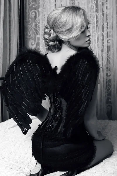 Sexy Mädchen mit blonden Haaren in luxuriöser Kleidung mit schwarzen Flügeln — Stockfoto
