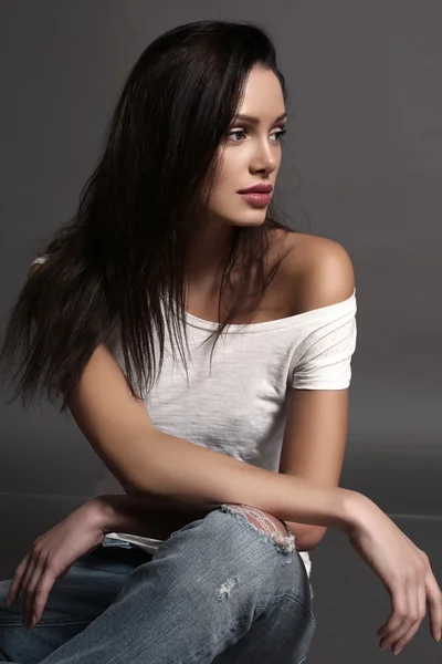 Woman with dark hair and natural makeup, wearing jeans — Stock Photo, Image