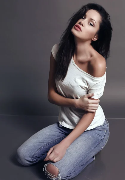 Женщина с темными волосами и натуральным макияжем, в джинсах — стоковое фото