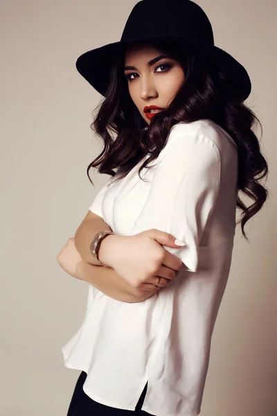 Hermosa chica morena en blusa blanca y elegante sombrero negro — Foto de Stock