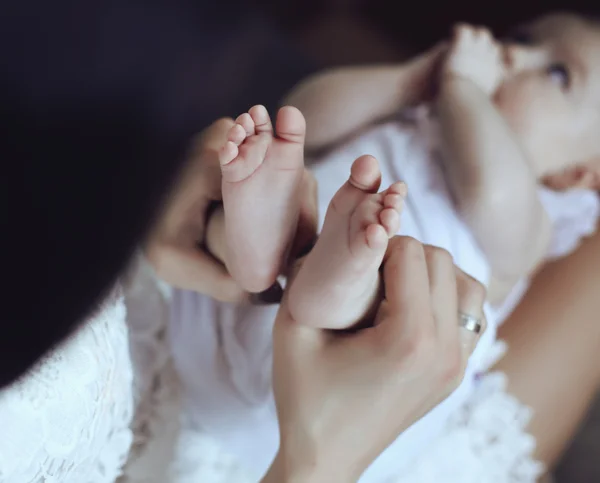 Matka pozowanie z nią mało noworodek, trzymając w ręce jej stopy — Zdjęcie stockowe