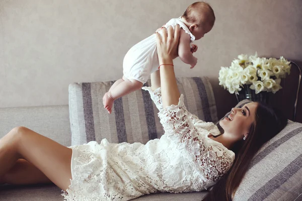 Bela jovem mãe com longos cabelos escuros posando com seu pequeno bebê adorável — Fotografia de Stock