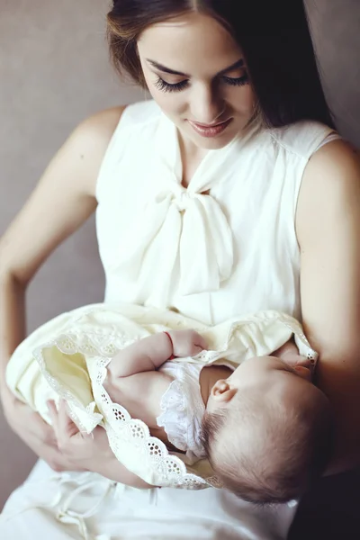 Schöne junge Mutter mit langen dunklen Haaren posiert mit ihrem kleinen entzückenden Baby — Stockfoto