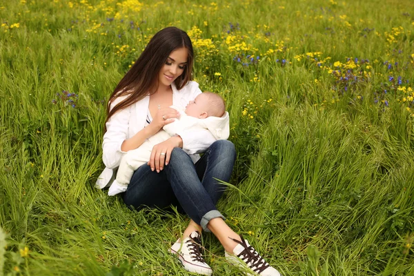 Hermosa madre divirtiéndose con su pequeño bebé lindo en el jardín de verano — Foto de Stock