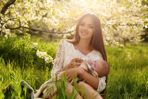 Beautiful mother posing with her little cute baby in blossom garden — Stock Photo, Image