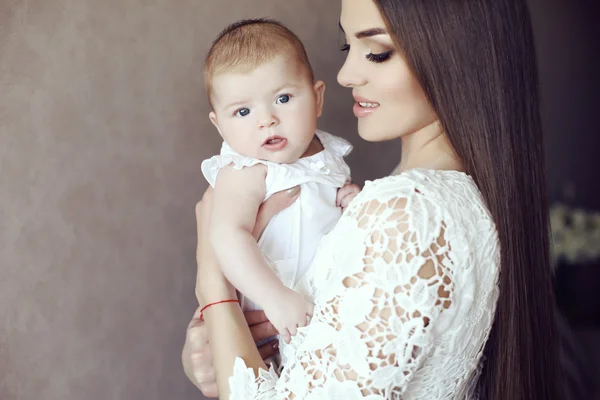 Schöne Mutter mit luxuriösen dunklen Haaren und ihrem kleinen Baby — Stockfoto