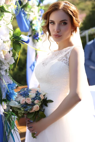 Чуттєва наречена з темним волоссям в розкішній мереживній весільній сукні з букетом — стокове фото