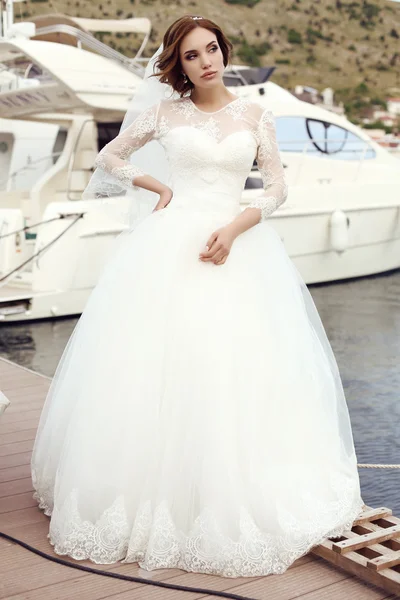 Bride with dark hair in luxurious lace wedding dress posing beside yacht — Stock Photo, Image