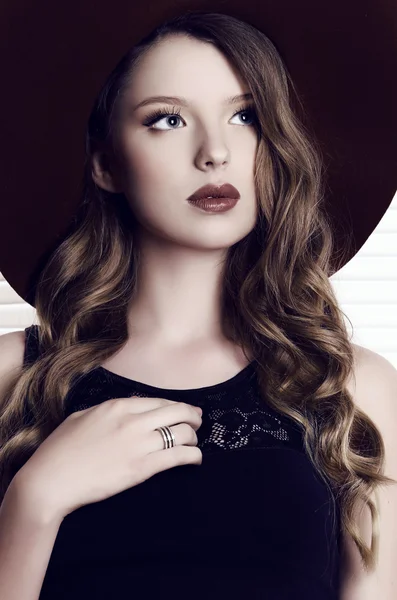 Girl with dark hair wearing black dress and elegant hat — Stock Photo, Image