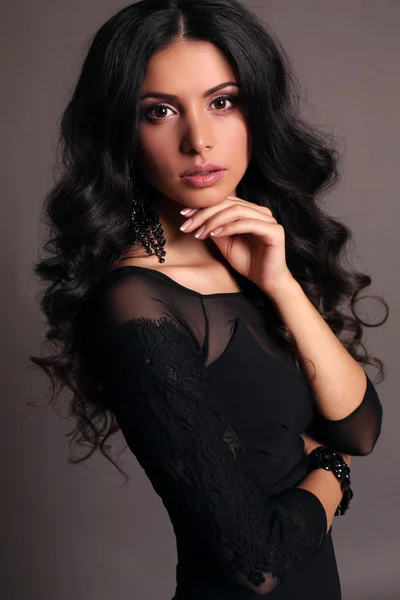 Mujer sensual con pelo rizado oscuro en elegante vestido negro con accesorios —  Fotos de Stock