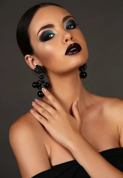 Beautiful girl with dark hair with bright extravagant makeup and bijou — Stockfoto