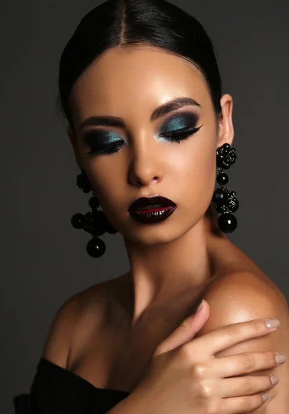 Schöne Mädchen mit dunklen Haaren mit hellem extravaganten Make-up und Bijou — Stockfoto