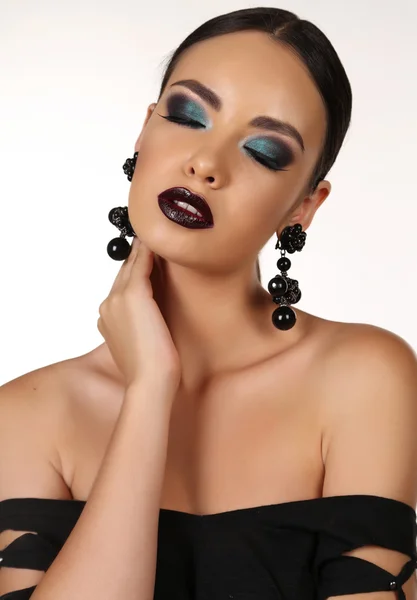 Beautiful girl with dark hair with bright extravagant makeup and bijou — Stockfoto