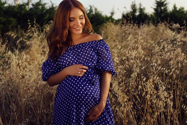 Zwangere vrouw in elegante jurk die zich voordeed op zomer field — Stockfoto