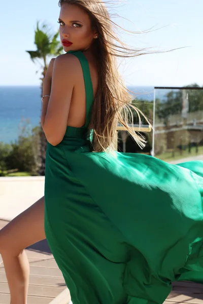 Ung kvinna med långa blonda hår i lyxig grön sidenklänning — Stockfoto