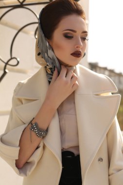 beautiful woman with dark hair in elegant coat and silk scarf 