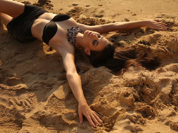 Fille sexy avec les cheveux noirs et la peau bronzée posant sur la plage — Photo