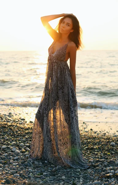 日落海滩上摆姿势优雅穿着黑头发的漂亮女人 — 图库照片