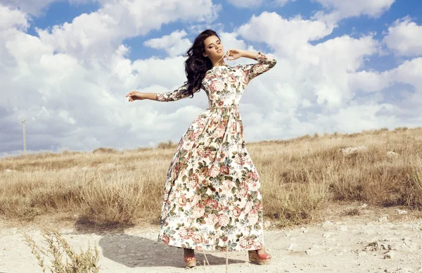 Mujer con cabello oscuro lleva lujoso vestido colorido posando en el campo de verano —  Fotos de Stock