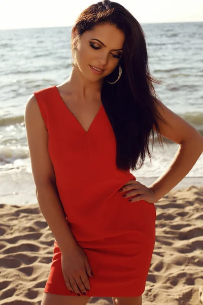 Beautiful girl in elegant red dress relaxing on summer beach — Zdjęcie stockowe