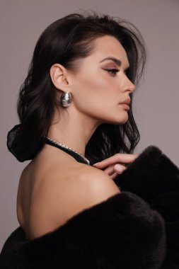 Güzel, seksi Slav bir kadının moda fotoğrafı. Koyu renk saçlı, lüks elbiseli, mücevherli.