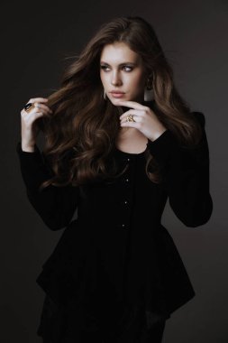 Slav bir kadının güzel, siyah saçlı, lüks elbiseli ve stüdyoda poz veren aksesuarlı bir fotoğrafı.