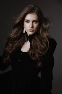 Slav bir kadının güzel, siyah saçlı, lüks elbiseli ve stüdyoda poz veren aksesuarlı bir fotoğrafı.