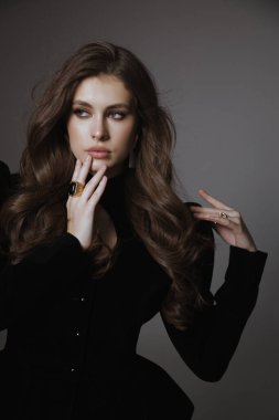 Slav bir kadının güzel, siyah saçlı, lüks elbiseli ve stüdyoda poz veren aksesuarlı bir fotoğrafı.