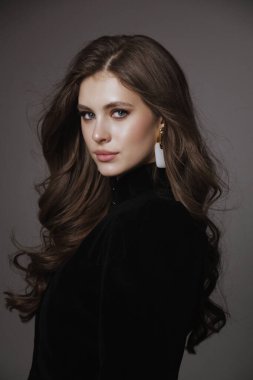 Slav bir kadının güzel, siyah saçlı, lüks elbiseli ve stüdyoda poz veren aksesuarlı bir fotoğrafı.