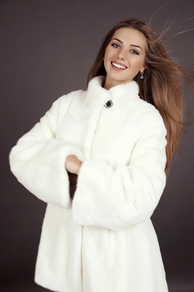 Schöne Frau mit langen Haaren trägt luxuriösen weißen Pelzmantel — Stockfoto