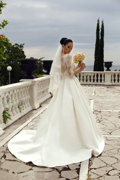 Jonge vrouw met lang donker haar in luxe kant trouwjurk — Stockfoto