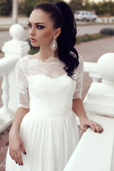 Mujer joven con pelo largo y oscuro en lujoso vestido de novia de encaje — Foto de Stock