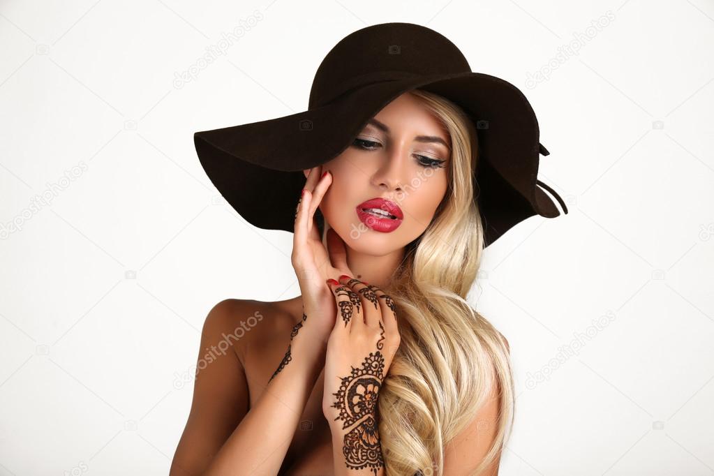 sensual woman in elegant black hat with henna tattoo on hands