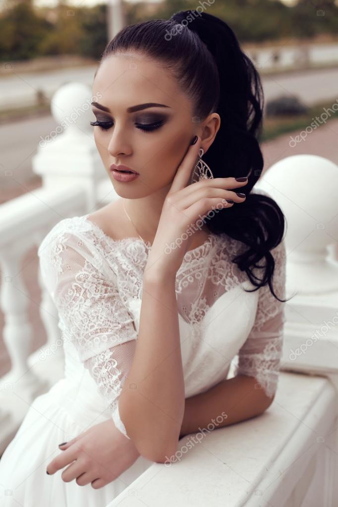 young woman with long dark hair in luxurious lace wedding dress