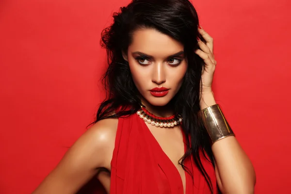 Sensual woman with dark hair wears elegant red dress and accessories — Stock Fotó