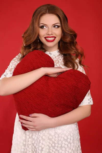 Jovem com cabelo escuro e maquiagem brilhante, em vestido elegante segurando grande coração vermelho — Fotografia de Stock