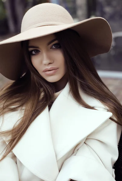 Glamour girl with dark straight hair wears luxurious beige coat with elegant hat, — Stock Photo, Image