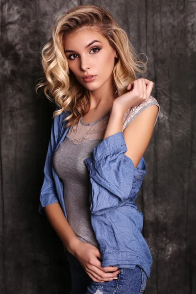 Beautiful woman with blond curly hair and evening makeup,wears jeans clothes — Stock Photo, Image
