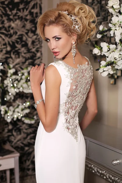 Gorgeous woman with blond hair wears luxurious wedding dress and bijou — Stock Photo, Image