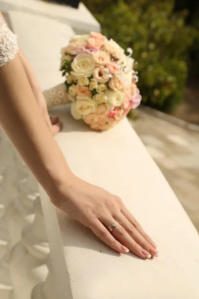 Mani della sposa con fede nuziale e mazzo di fiori — Foto Stock