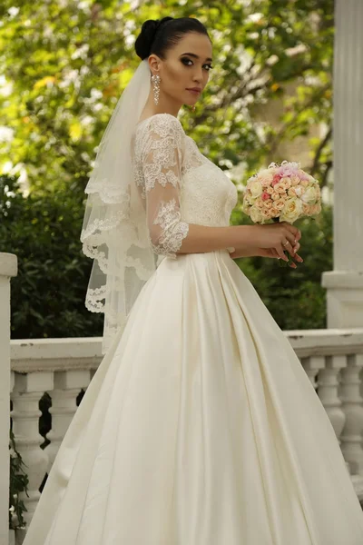 Wunderschöne Braut mit dunklen Haaren trägt elegantes Hochzeitskleid — Stockfoto