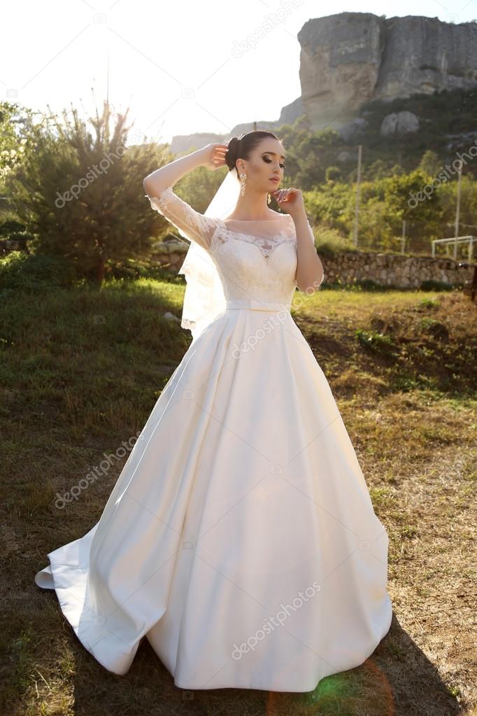 gorgeous bride with dark hair wears elegant wedding dress 