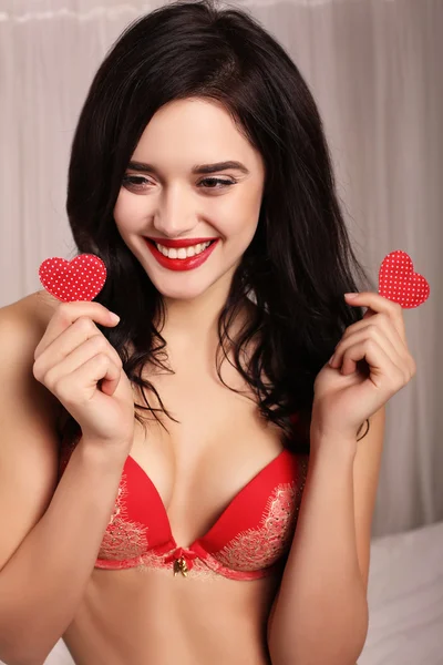 Sexy girl in elegant lace lingerie, holding red heart, symbol of Valentine's day — стокове фото