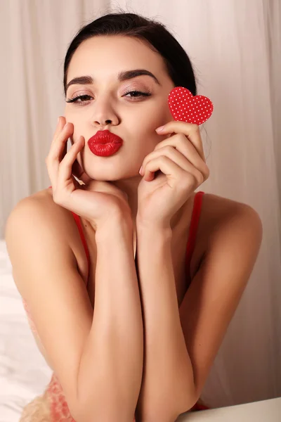 Sexy ragazza in lingerie di pizzo elegante, tenendo il cuore rosso, simbolo di San Valentino — Foto Stock