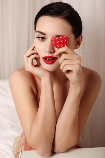 Ragazza sexy con i capelli scuri indossa lingerie elegante pizzo, tenendo il cuore rosso — Foto Stock