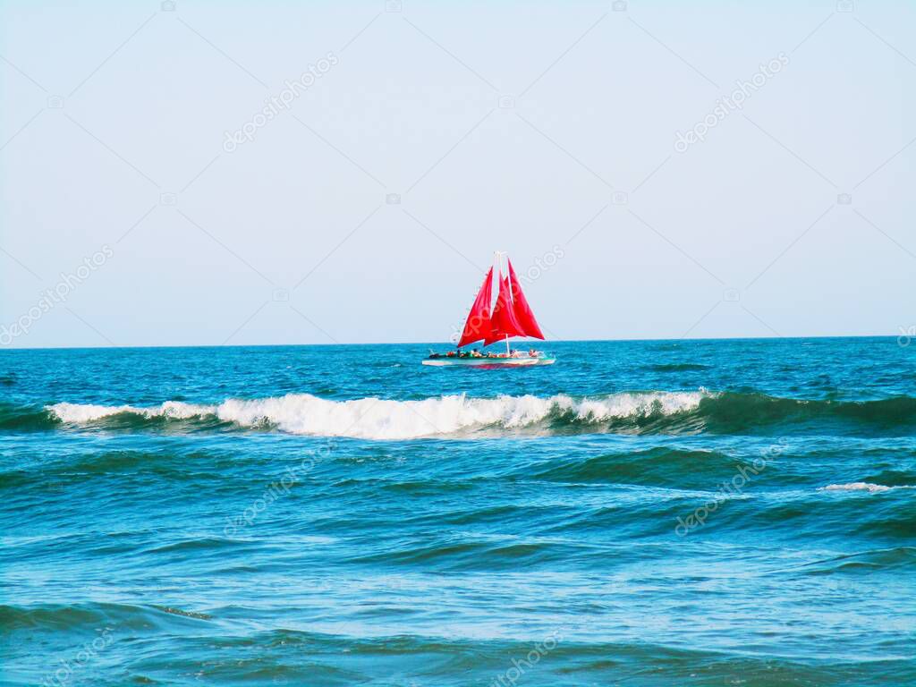 A boat merrily running in the open sea against the background of the blue cloudless sky 