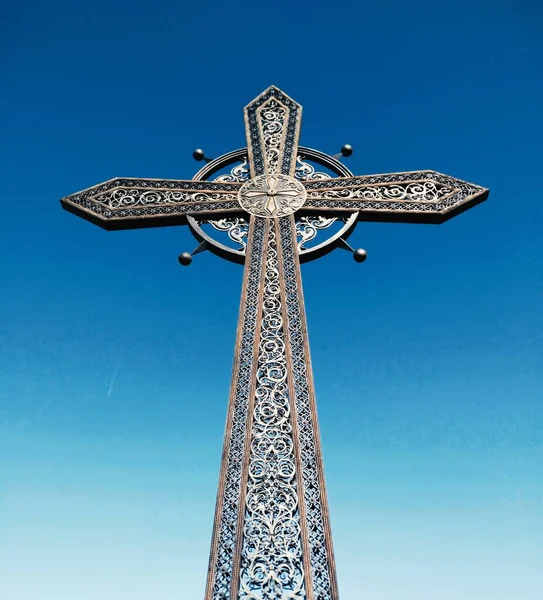 Forged Orthodox cross against the background of the blue cloudless sky