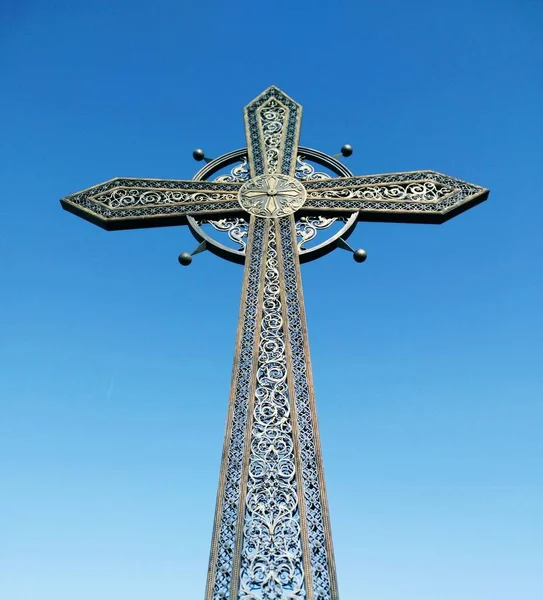 Forged Orthodox cross against the background of the blue cloudless sky