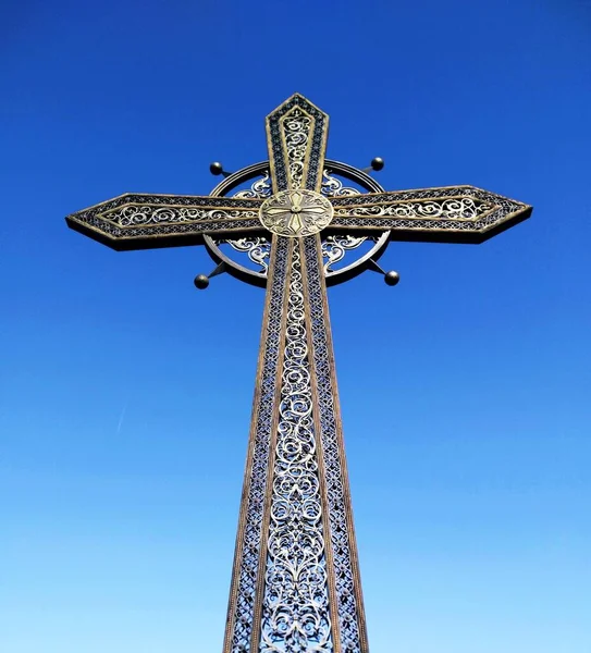 Forged Orthodox cross against the background of the blue cloudless sky